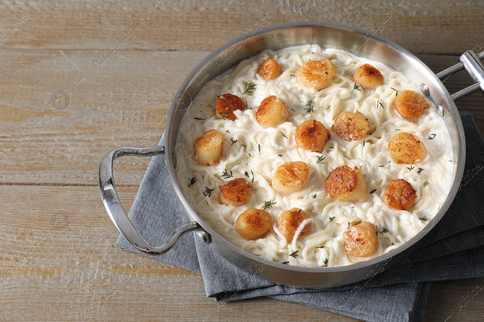 Photo of Delicious scallop pasta in pan on wooden table