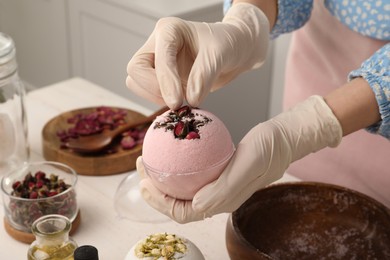 Woman in gloves making bath bomb at white table indoors, closeup