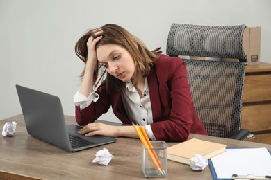 Sad businesswoman working at wooden table in office