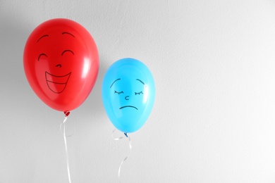 Photo of Air balloons with drawn sad and happy faces on white background. Space for text