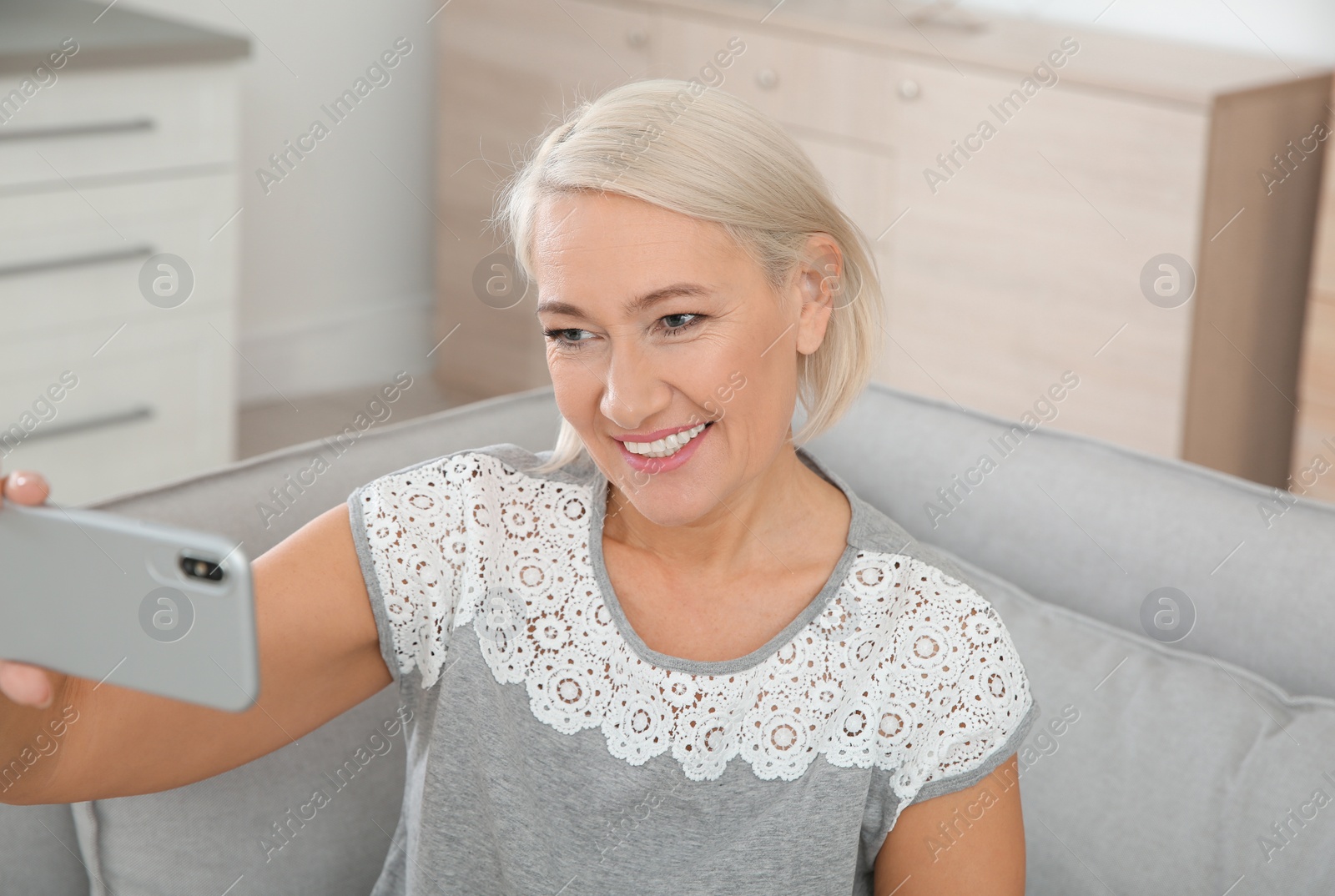 Photo of Mature woman laughing while taking selfie at home