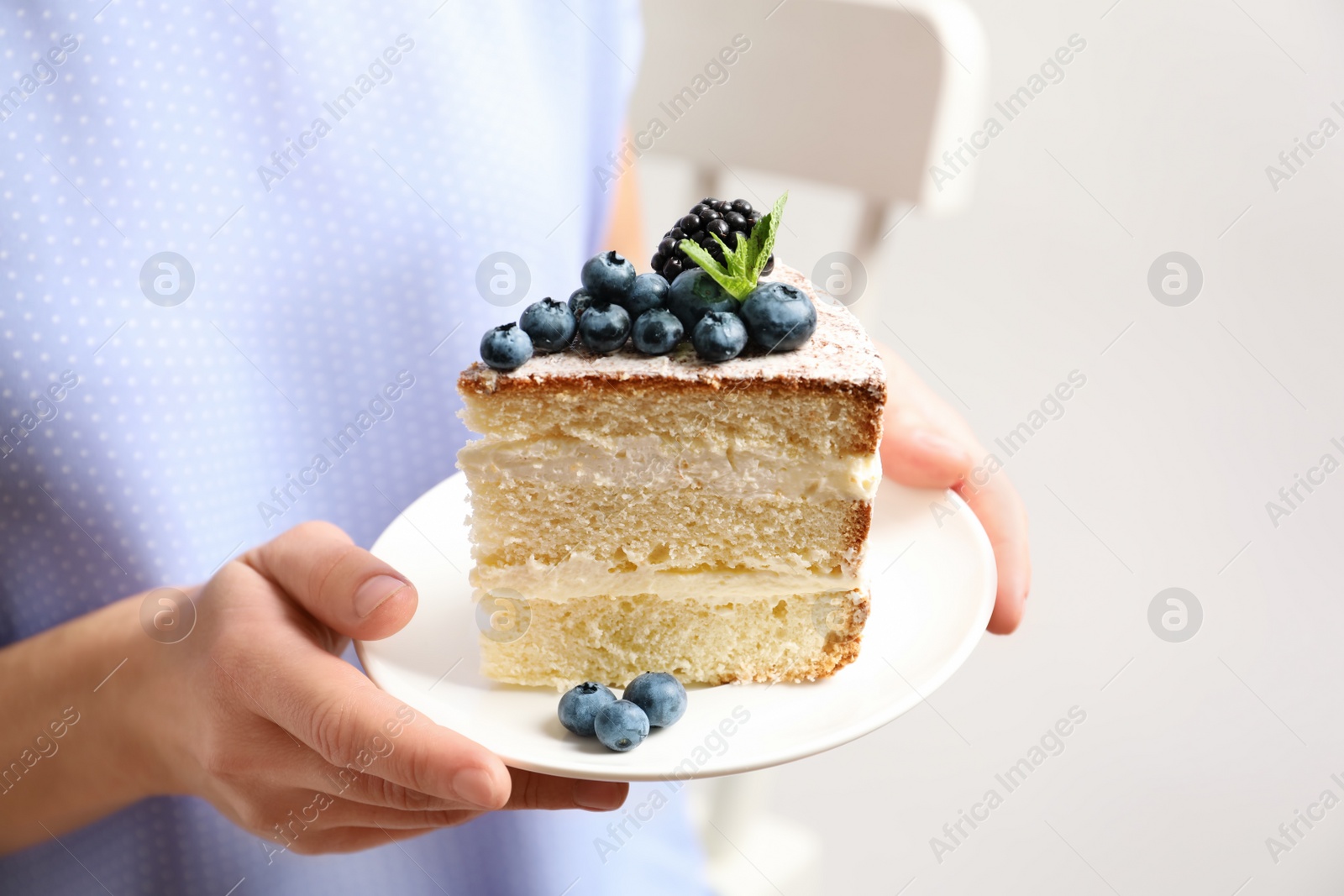 Photo of Woman holding piece of delicious homemade cake with fresh berries on plate, closeup