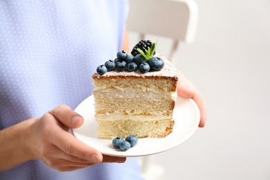 Photo of Woman holding piece of delicious homemade cake with fresh berries on plate, closeup