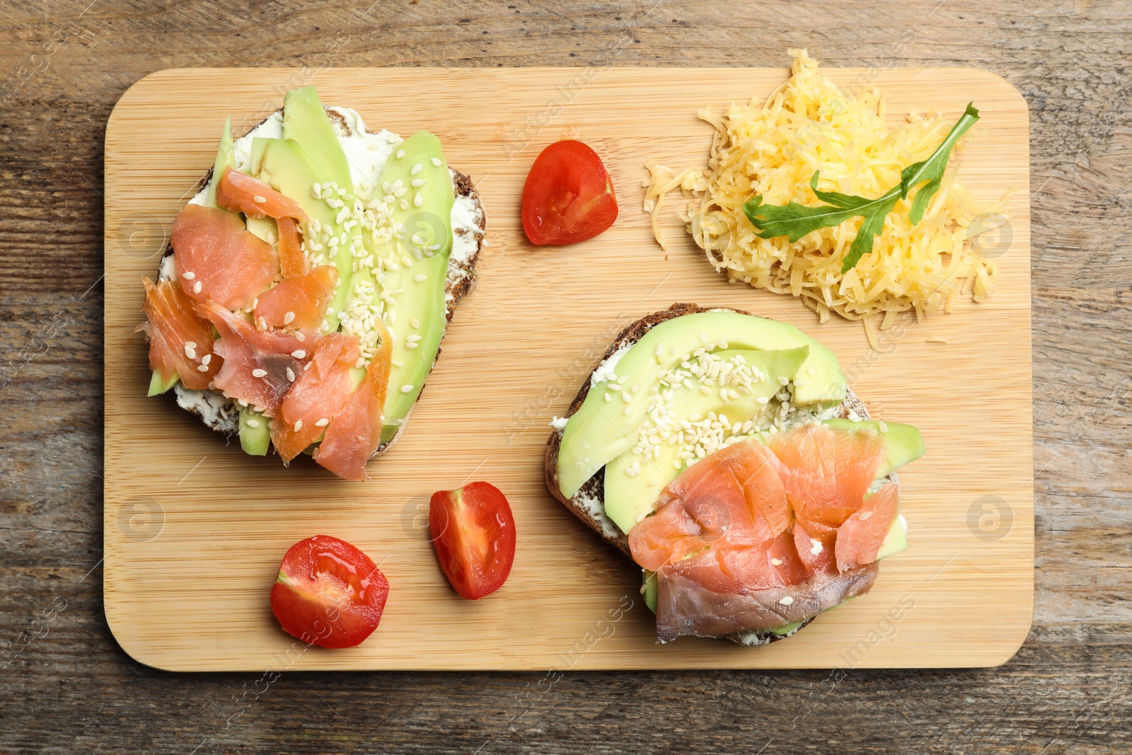 Photo of Delicious sandwiches with sliced salmon and avocado on wooden table, top view