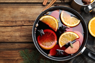 Delicious mulled wine and ingredients on wooden table, flat lay