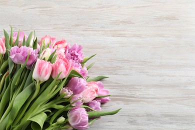 Photo of Beautiful bouquet of colorful tulip flowers on wooden table, top view. Space for text