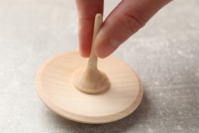 Photo of Woman playing with wooden spinning top at grey textured background, closeup