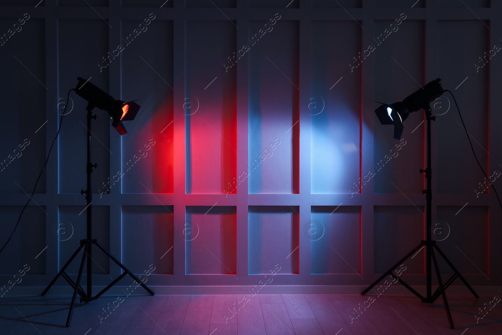 Photo of Bright red and blue spotlights near wall in dark room, space for text