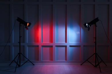 Photo of Bright red and blue spotlights near wall in dark room, space for text