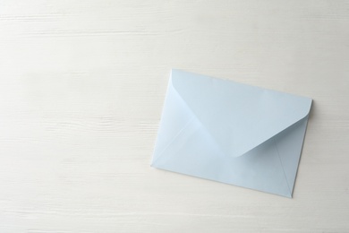 Photo of Light paper envelope on white wooden table, top view. Space for text