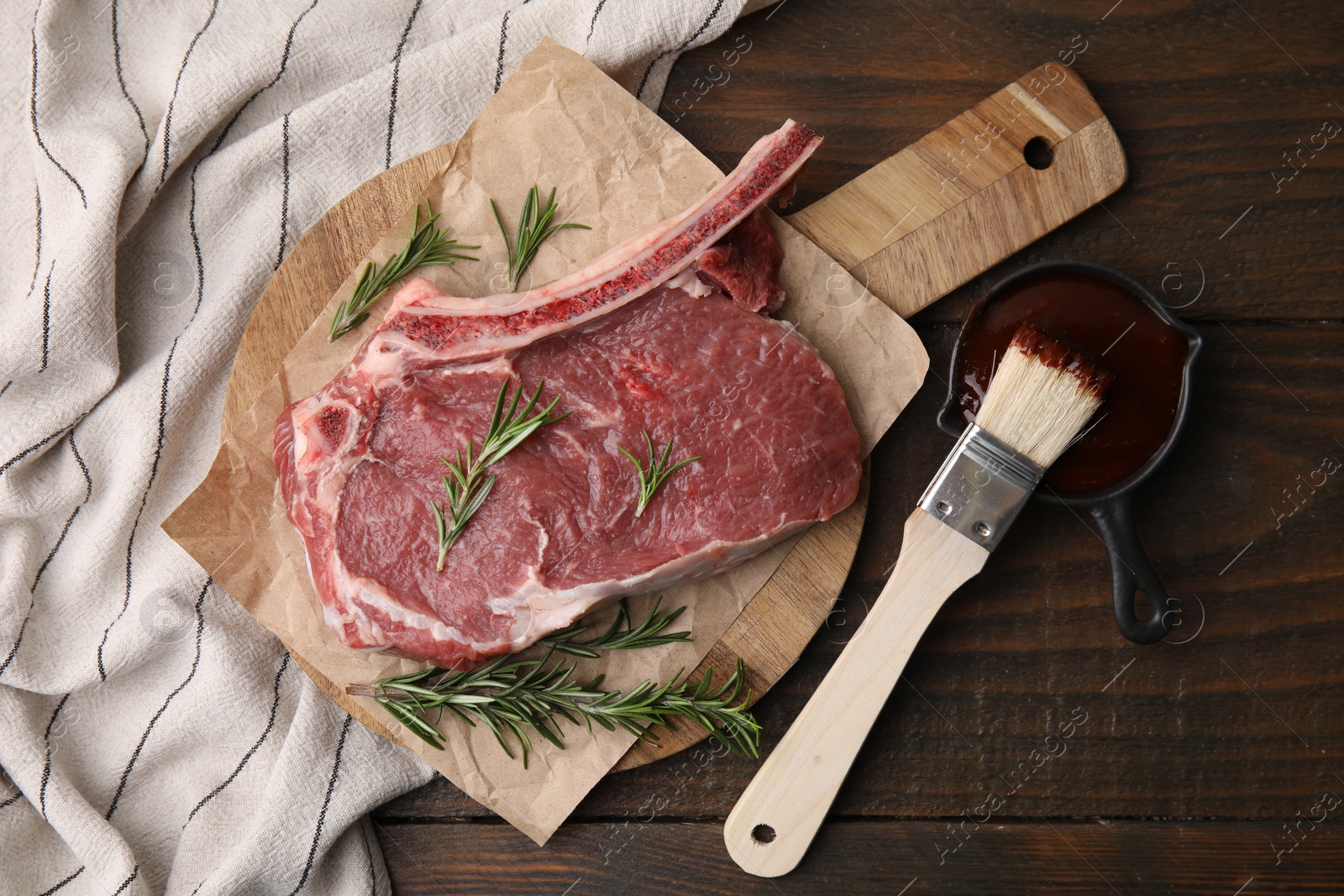 Photo of Raw meat, rosemary and marinade on wooden table, flat lay