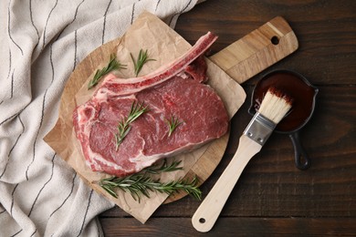 Photo of Raw meat, rosemary and marinade on wooden table, flat lay