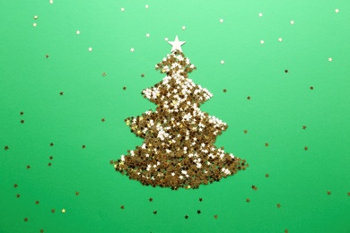 Photo of Christmas tree made of confetti stars on green background, flat lay