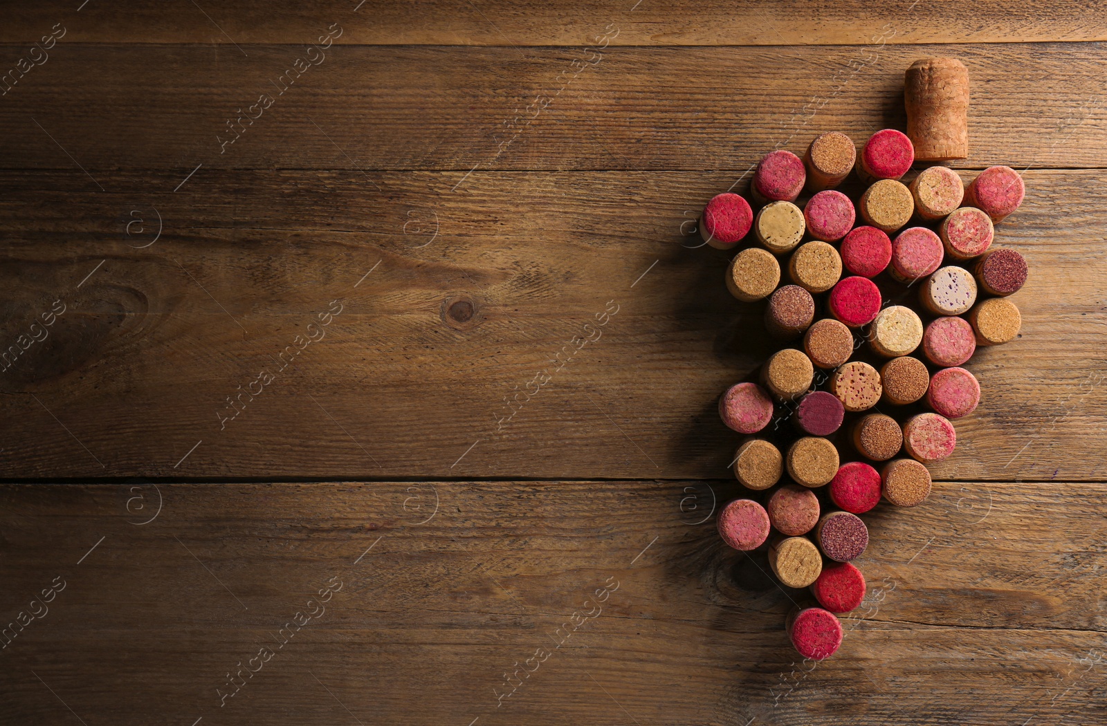 Photo of Grape made of wine bottle corks on wooden table, top view. Space for text