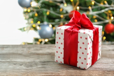 Photo of Beautiful gift box and blurred Christmas tree on background