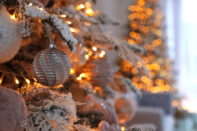 Photo of Christmas tree branch with balls indoors, closeup. Festive interior decoration