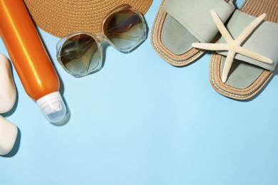 Sunscreen, starfish, stones and beach accessories on light blue background, flat lay and space for text. Sun protection