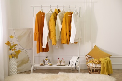 Rack with stylish warm clothes, shoes and accessories in modern dressing room