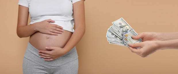 Image of Surrogacy. Intended mother with money and pregnant woman on beige background, closeup. Banner design