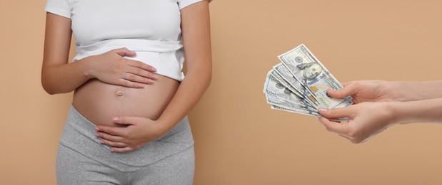 Surrogacy. Intended mother with money and pregnant woman on beige background, closeup. Banner design