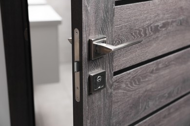 Open wooden door with metal handle, closeup