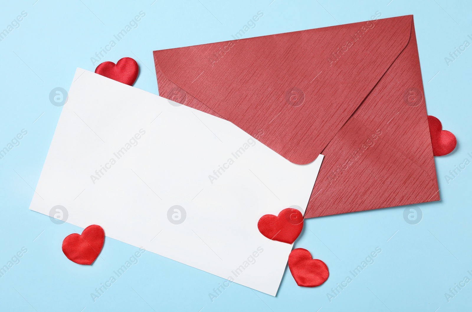 Photo of Blank card, envelope and decorative hearts on light blue background, flat lay with space for text. Valentine's Day celebration