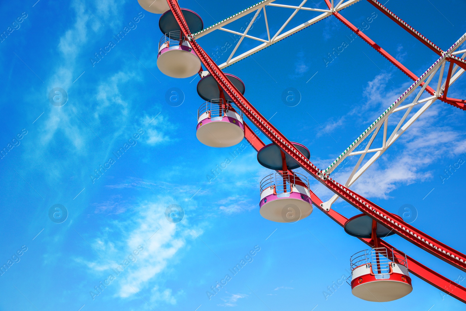 Photo of Beautiful large Ferris wheel against blue sky, low angle view