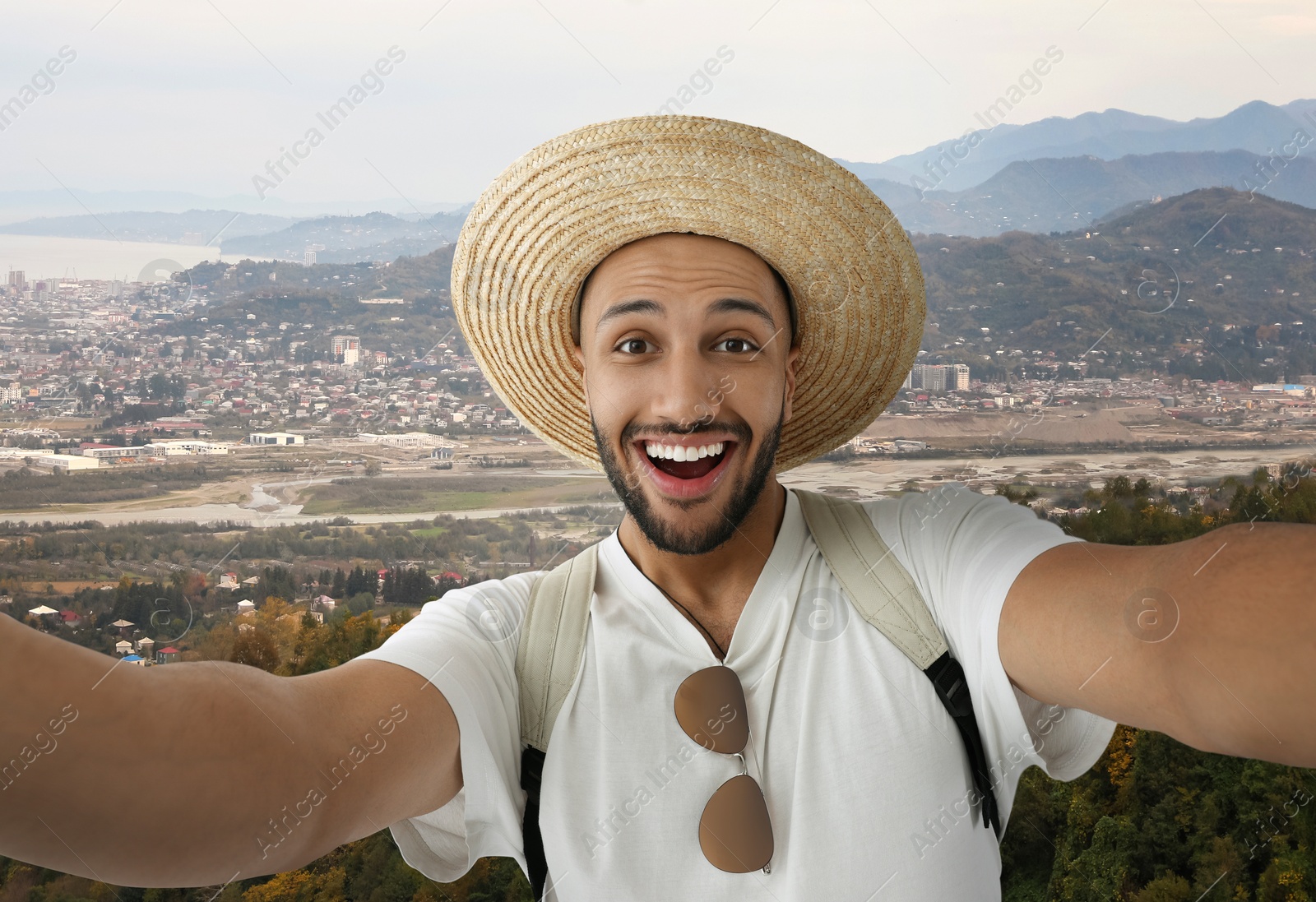 Image of Smiling young man in straw hat taking selfie in mountains