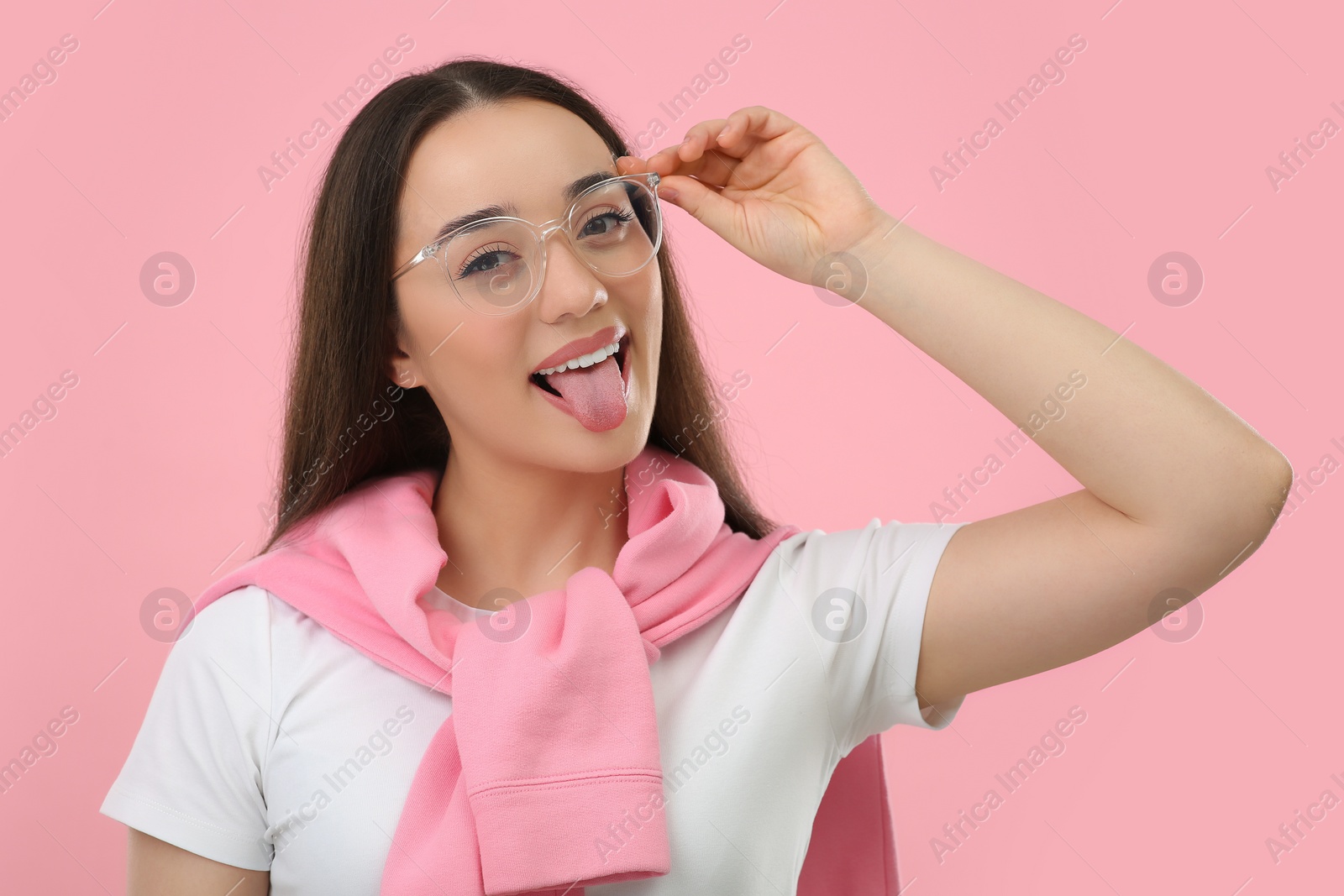 Photo of Happy woman showing her tongue on pink background