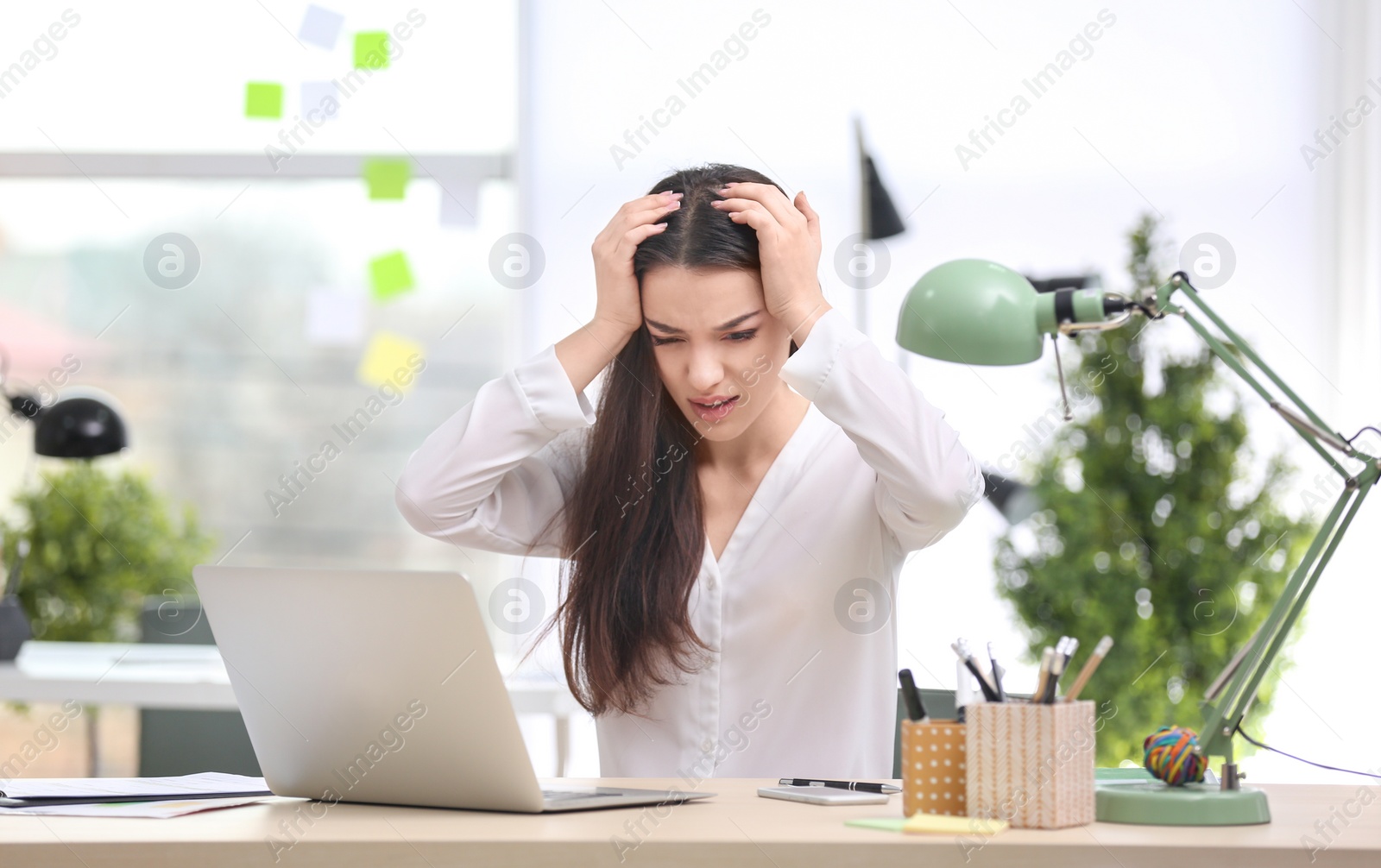 Photo of Young woman suffering from headache in office