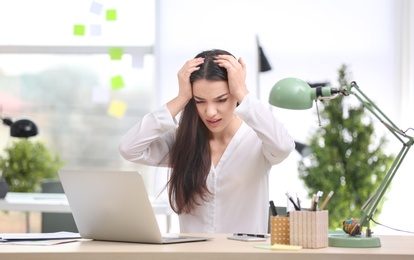 Young woman suffering from headache in office