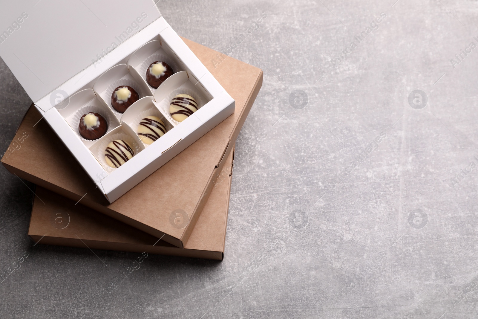 Photo of Delicious chocolate candies and box on light grey table, top view with space for text. Production line