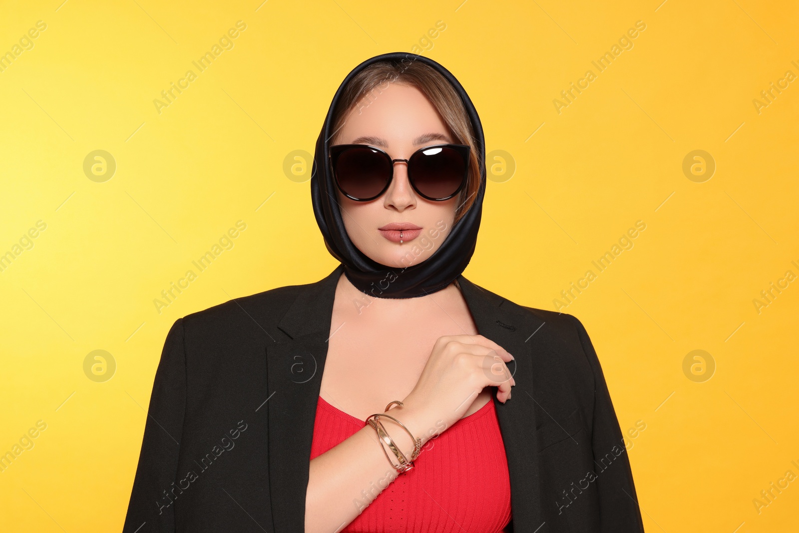 Photo of Young woman with lip piercing and sunglasses on yellow background