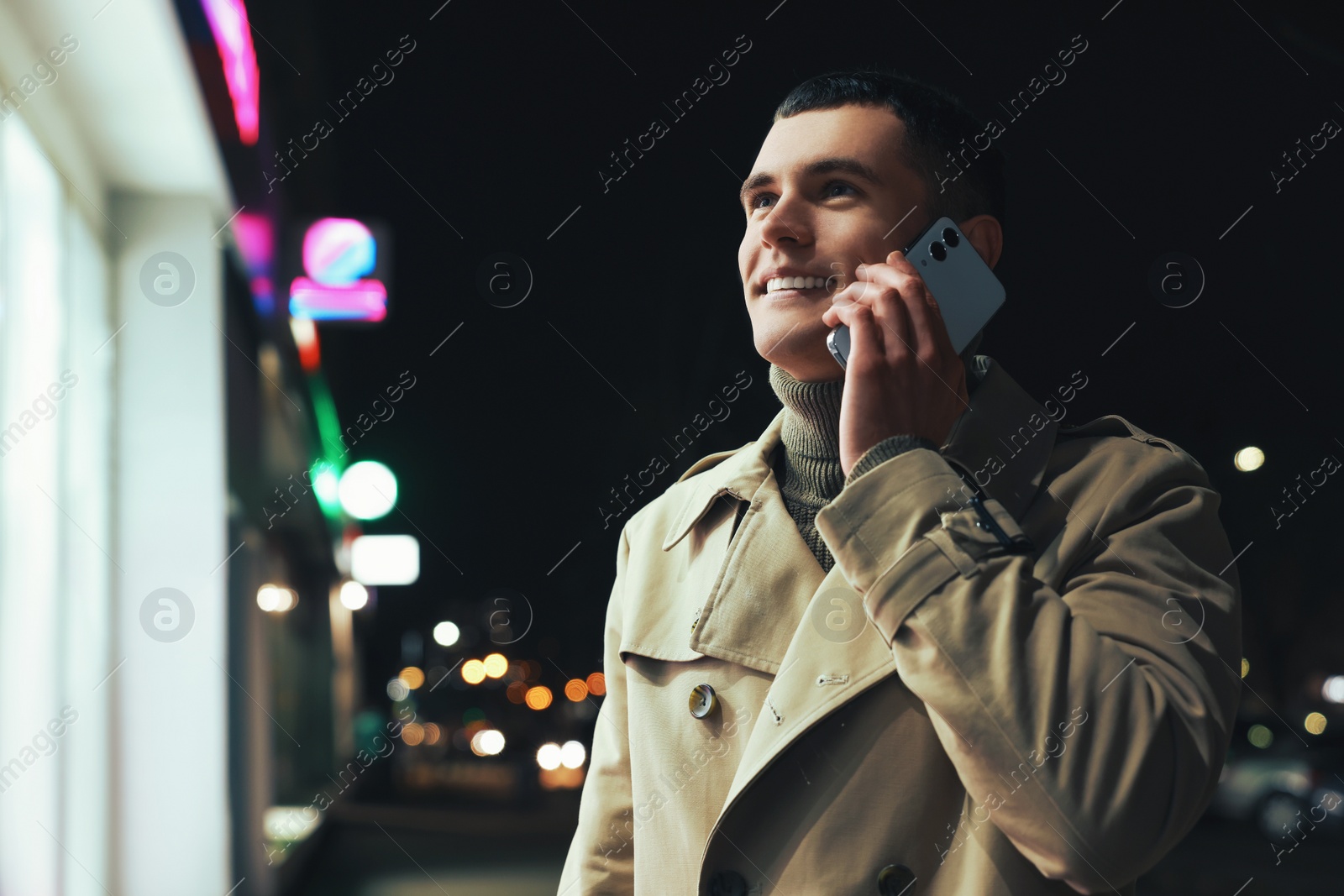 Photo of Man talking by smartphone on night city street, space for text