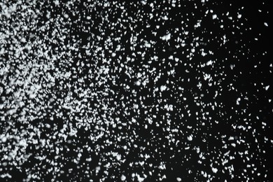 Photo of White snow falling down on black background