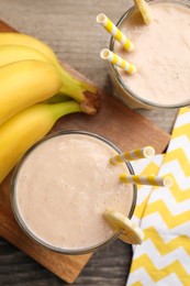 Glasses with banana smoothie on wooden table, flat lay
