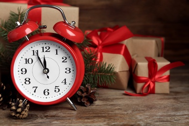 Christmas gifts, alarm clock and pine cones on wooden table, space for text. Boxing day