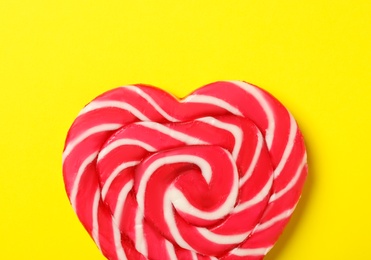 Photo of Sweet heart shaped lollipop on yellow background, top view. Valentine's day celebration