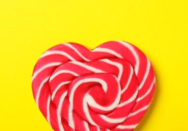 Sweet heart shaped lollipop on yellow background, top view. Valentine's day celebration