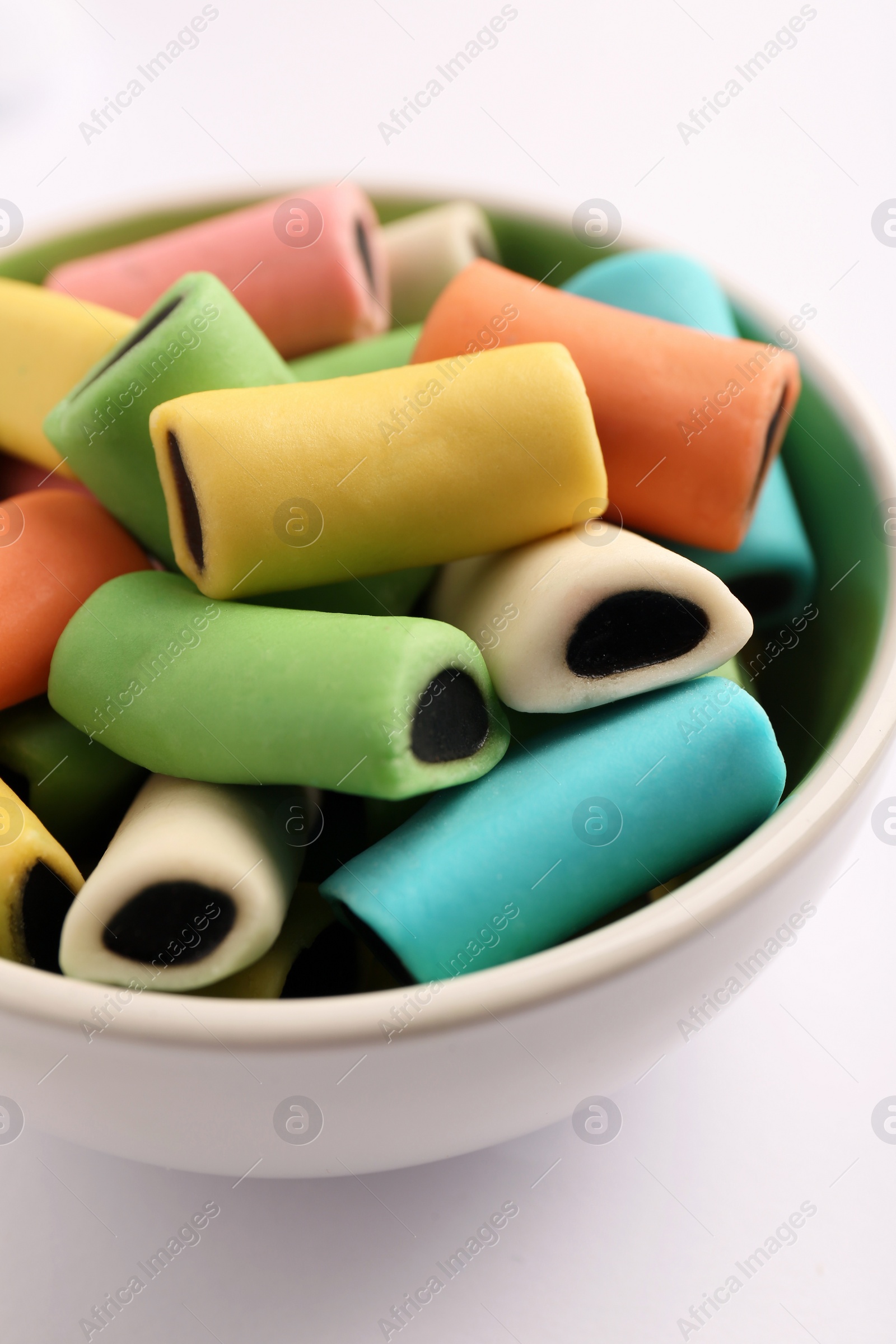 Photo of Bowl of tasty liquorice candies on light background, closeup