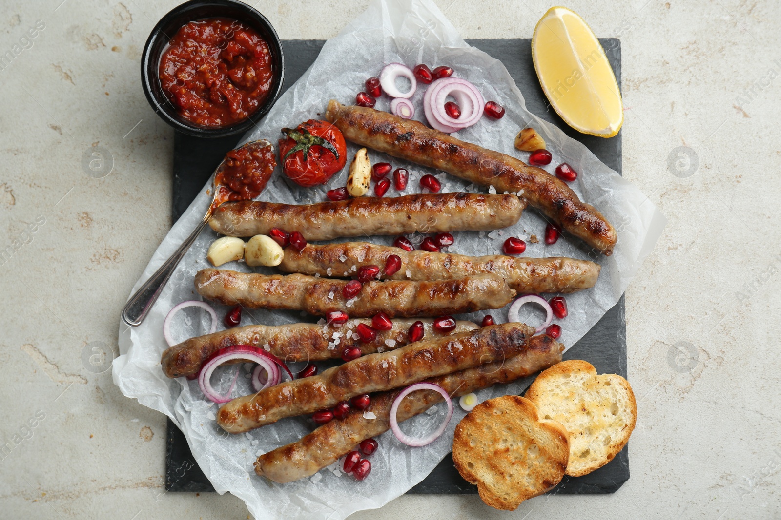 Photo of Tasty grilled sausages served on light table, flat lay