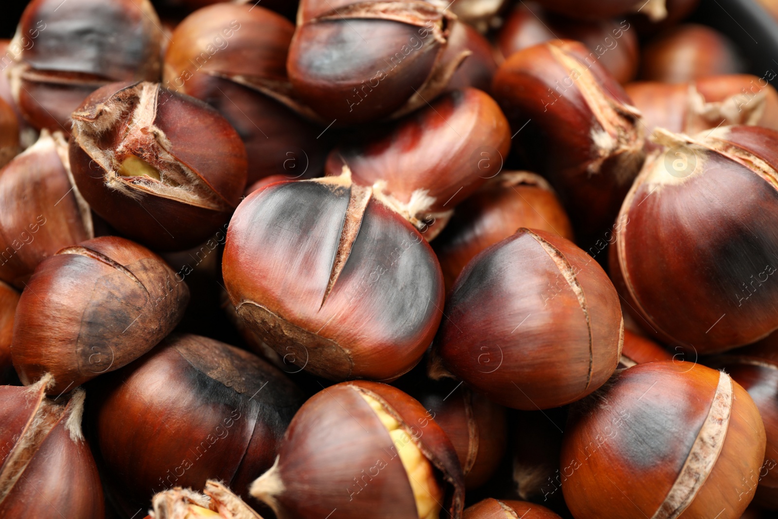 Photo of Pile of delicious edible roasted chestnuts as background, closeup