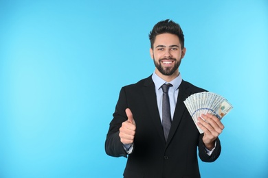 Photo of Portrait of happy young businessman with money on color background. Space for text