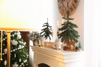 Photo of Small fir trees and Christmas decor on mantelpiece indoors, space for text. Interior design