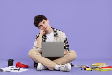 Photo of Portrait of student with laptop and stationery sitting on purple background