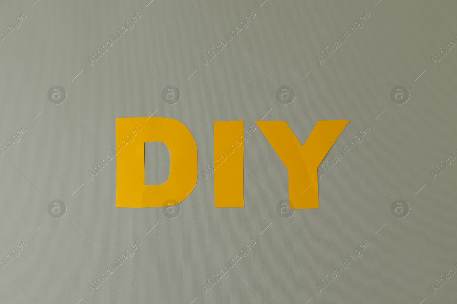 Photo of Abbreviation DIY made of letters on light grey background, flat lay