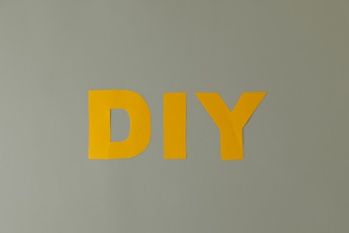 Photo of Abbreviation DIY made of letters on light grey background, flat lay