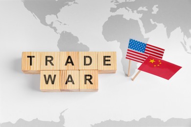 Words Trade War made of wooden cubes, American and Chinese flags on world map, above view