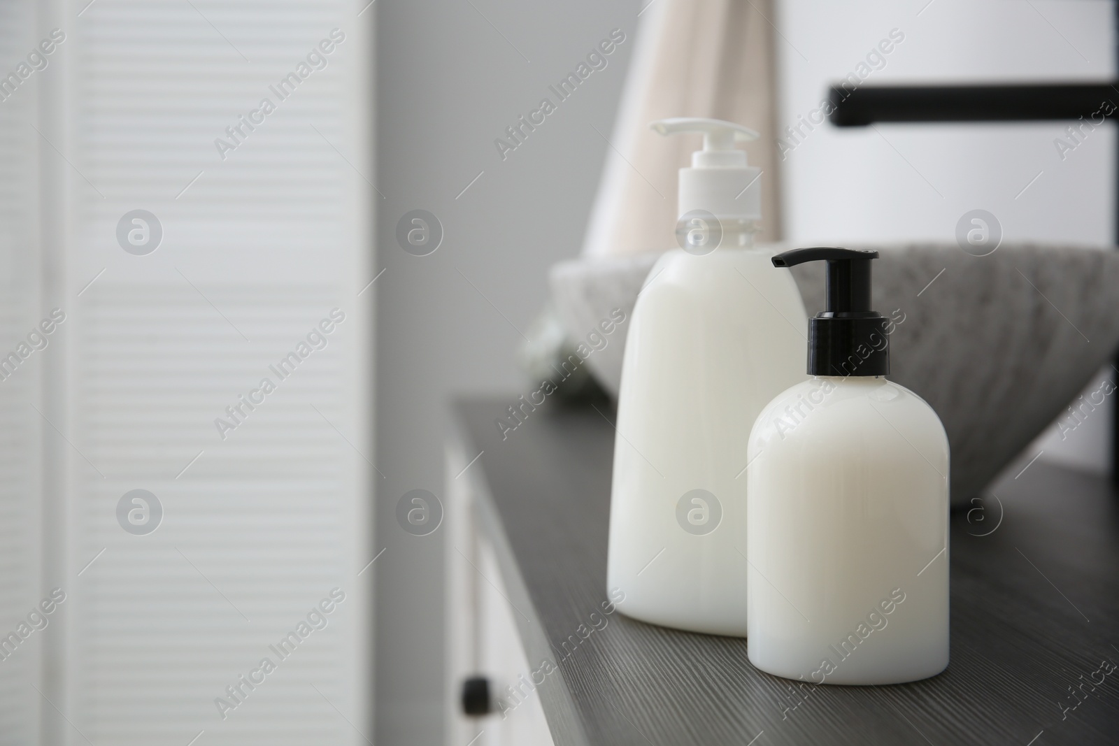 Photo of Dispensers of liquid soap on countertop in bathroom. Space for text