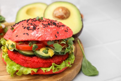 Tasty pink vegan burger with vegetables, patty and microgreens on white tiled table, closeup. Space for text